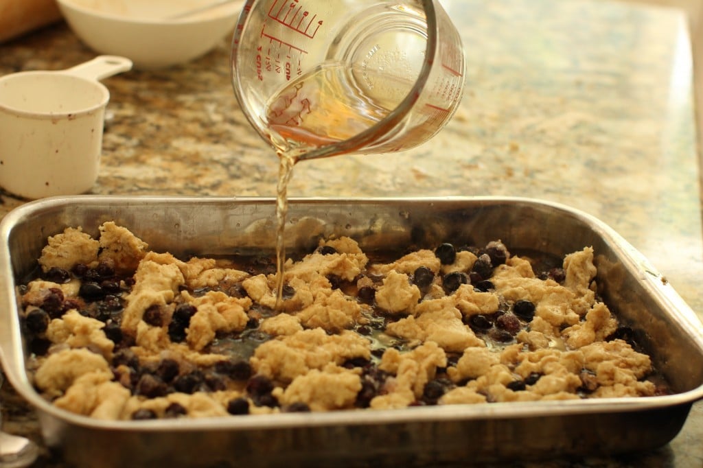 pouring the syrup over the saskatoon cobbler