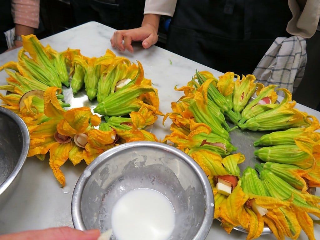 chicken breast in orange sauce, stuffed zucchini blossoms ready for frying