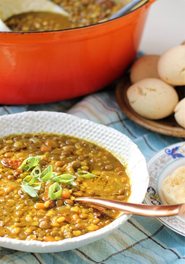 a bowl of golden lentil soup with green onion garnish