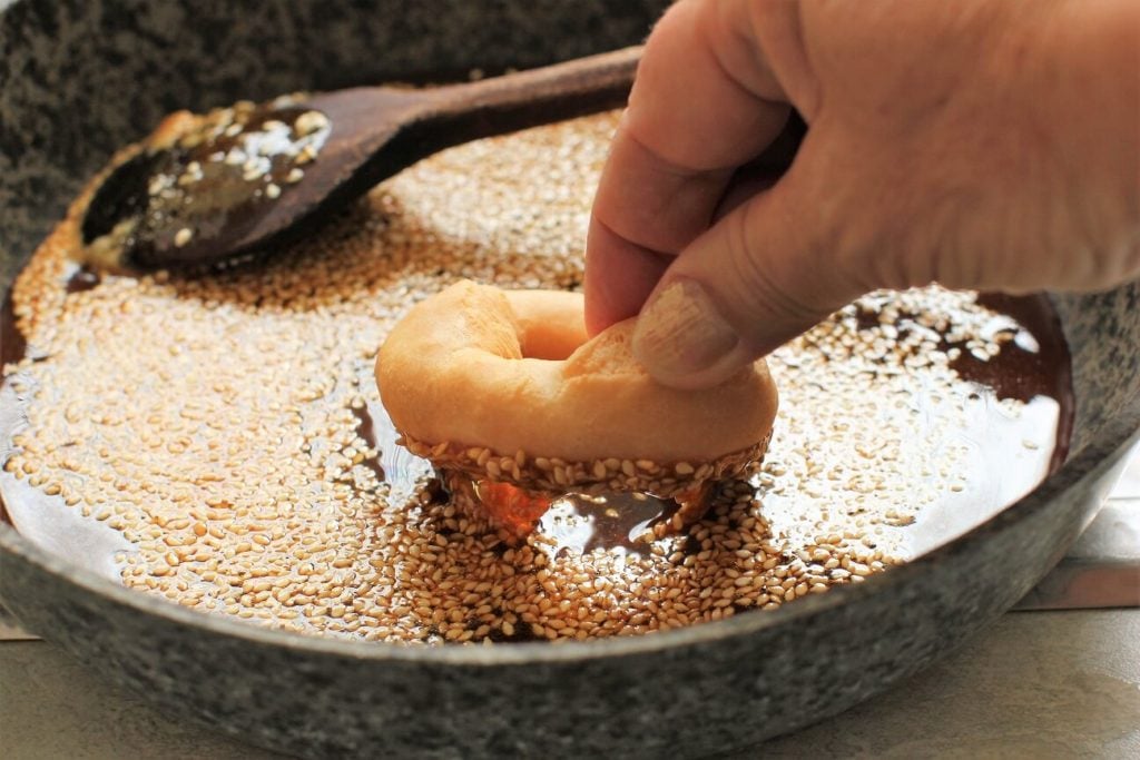 dipping the Cambodian donuts in the burnt sugar and sesame glaze