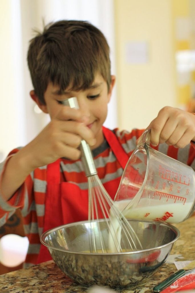 Eric adds the milk to the egg for the homemade vanilla pudding