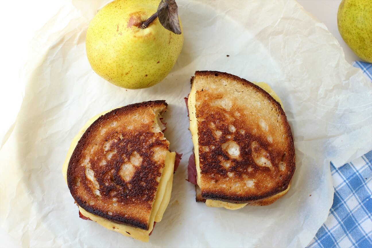 one bite out of the pear and pastrami grilled cheese sandwich