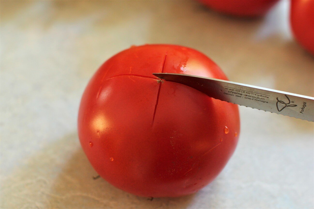 cutting an X into a tomato for blanching and peeling
