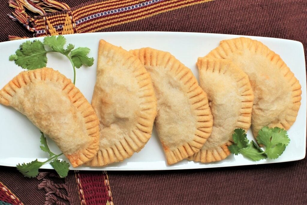 white platter with 5 gluten free empanadas on it in a row