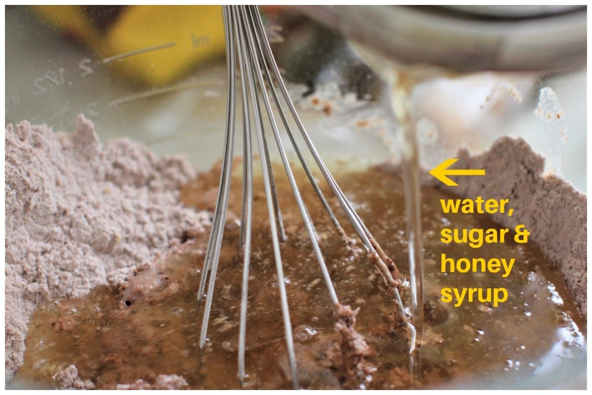 pouring the honey syrup into the dry ingredients and whisking it.