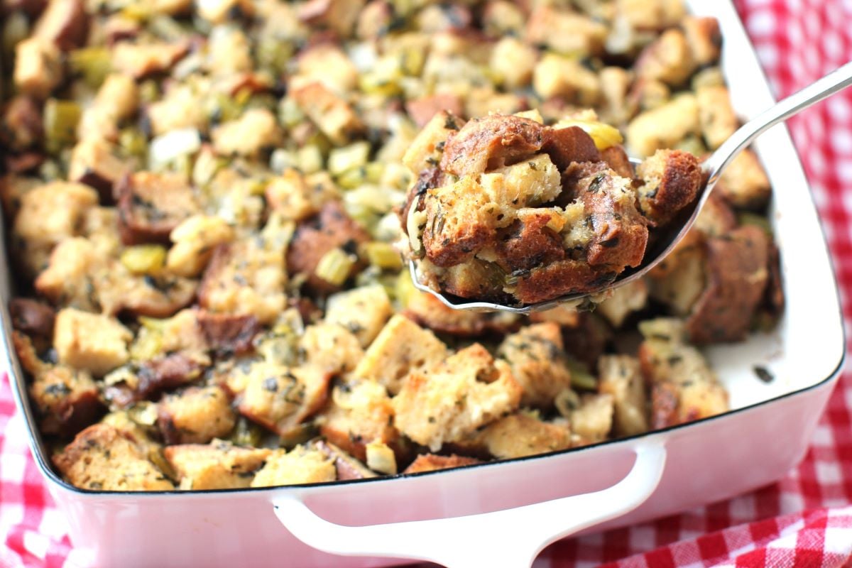 a serving spoon full of stuffing held above the pan.