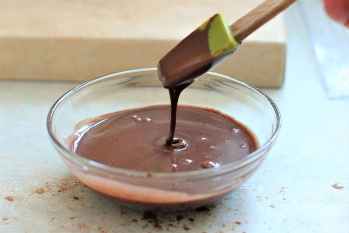 lifting a spoonful of chocolate icing and letting it dribble back into the bowl.