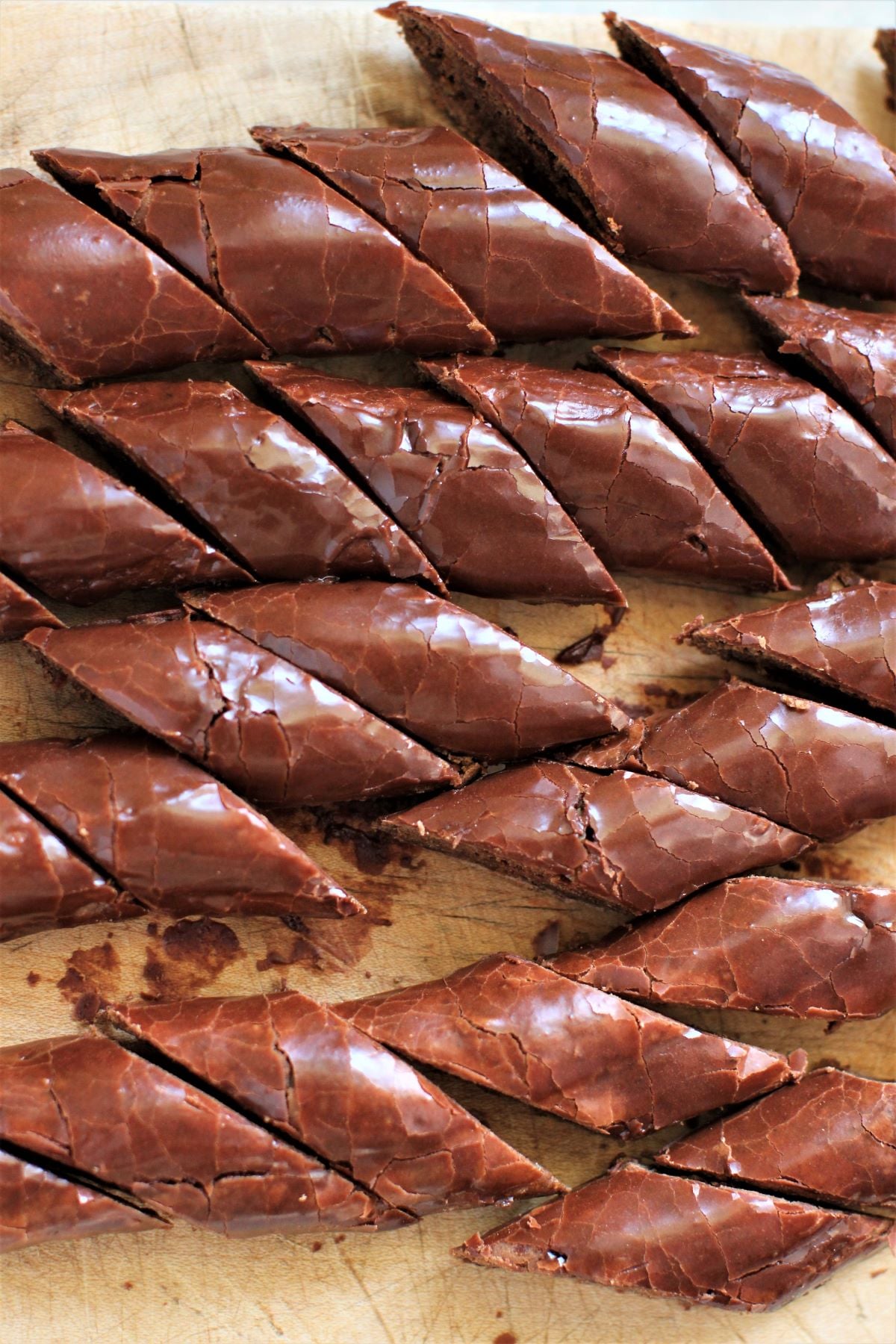 looking down at a pile of the cut and iced cookies on a wooden cutting board.