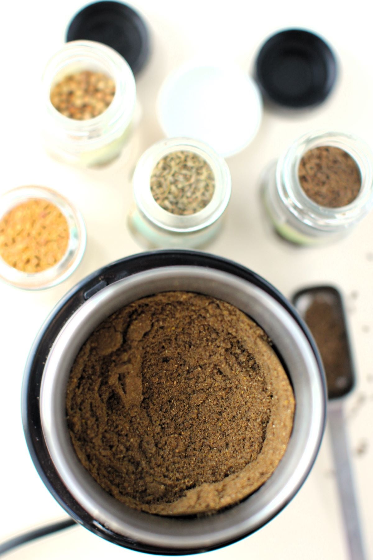 looking down into the spice grinder to see the finished bread spice, with spice jars in background.