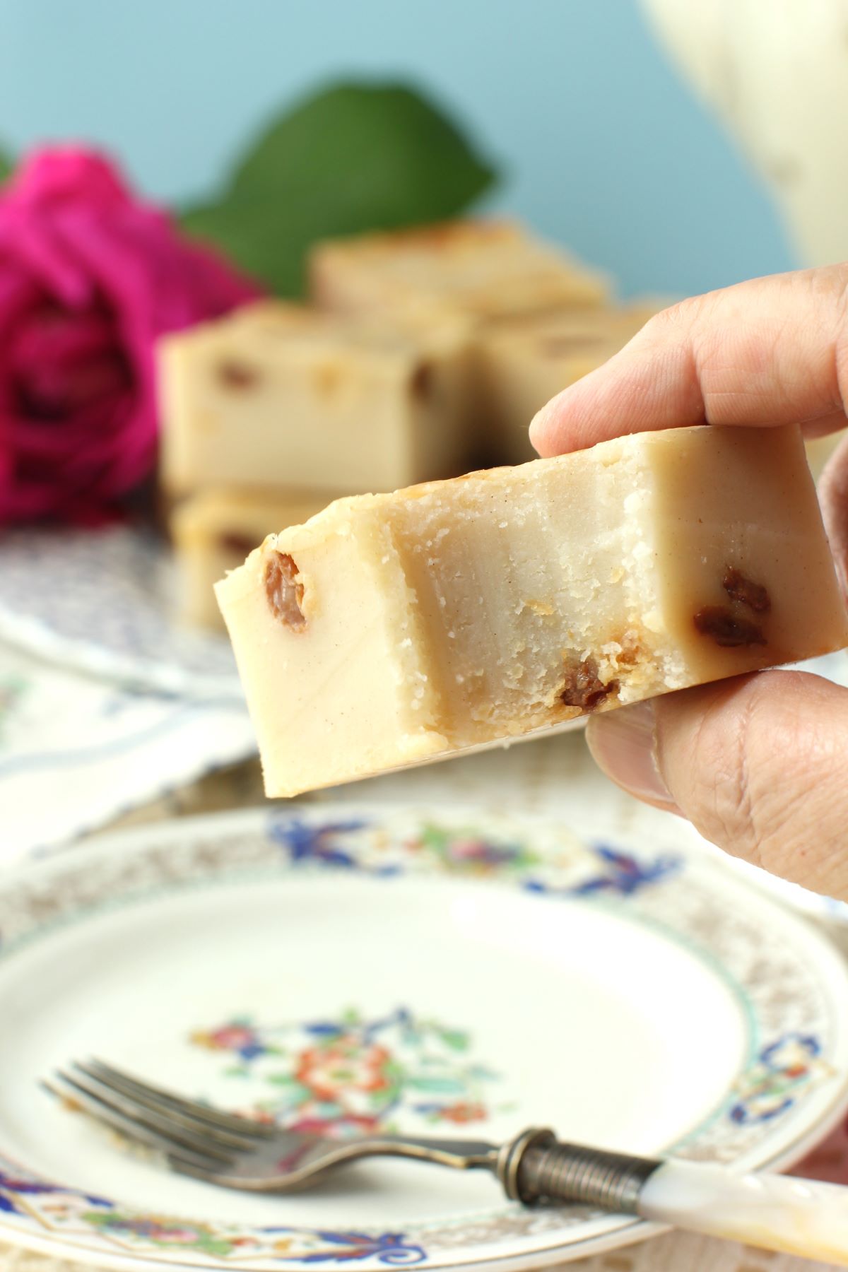 Lifting up a square of the cake with a bite taken out of it.