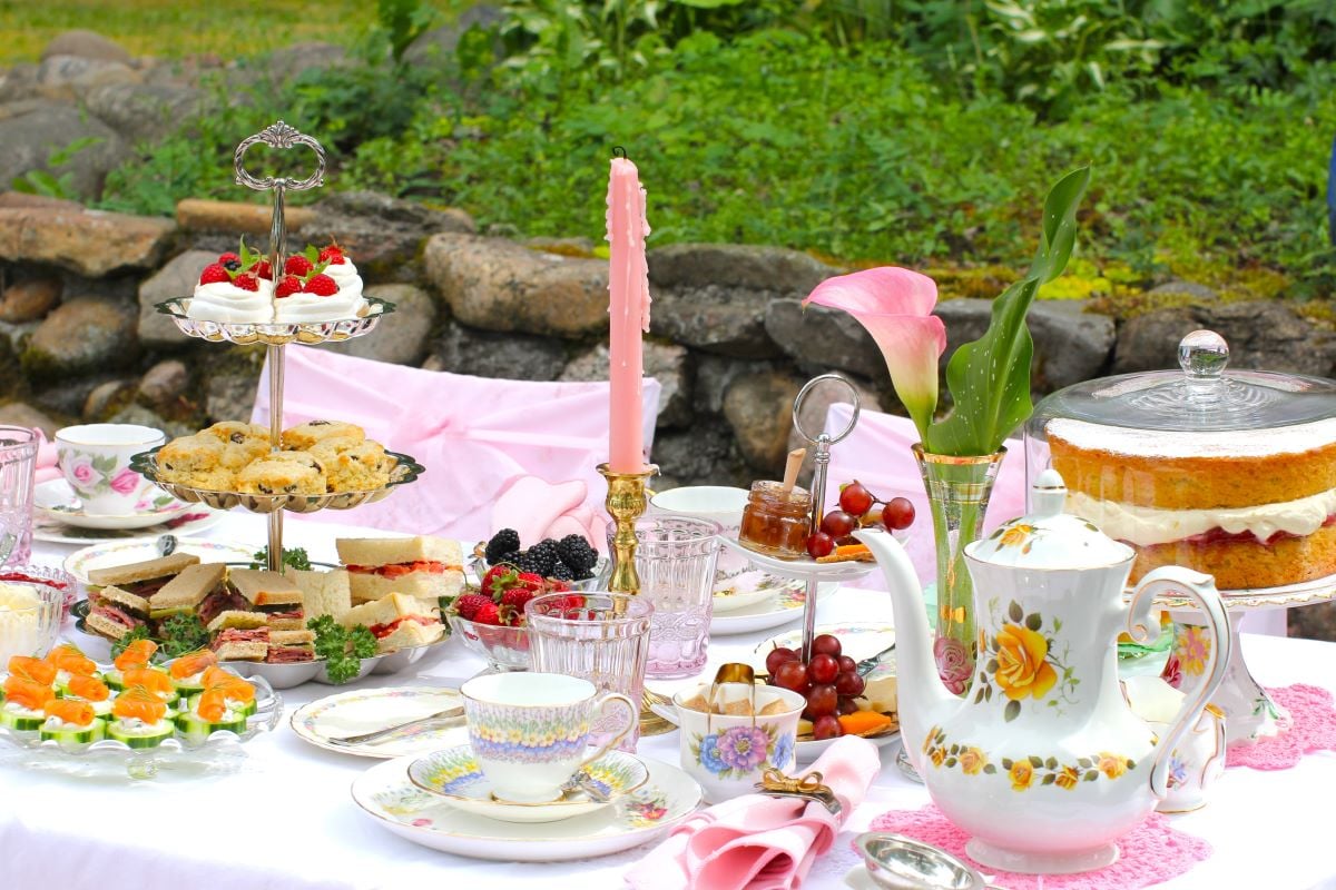 Afternoon tea table set ourside, with 3-tiered cake stand on left and Gluten Free Victoria Sponge Cake on right.