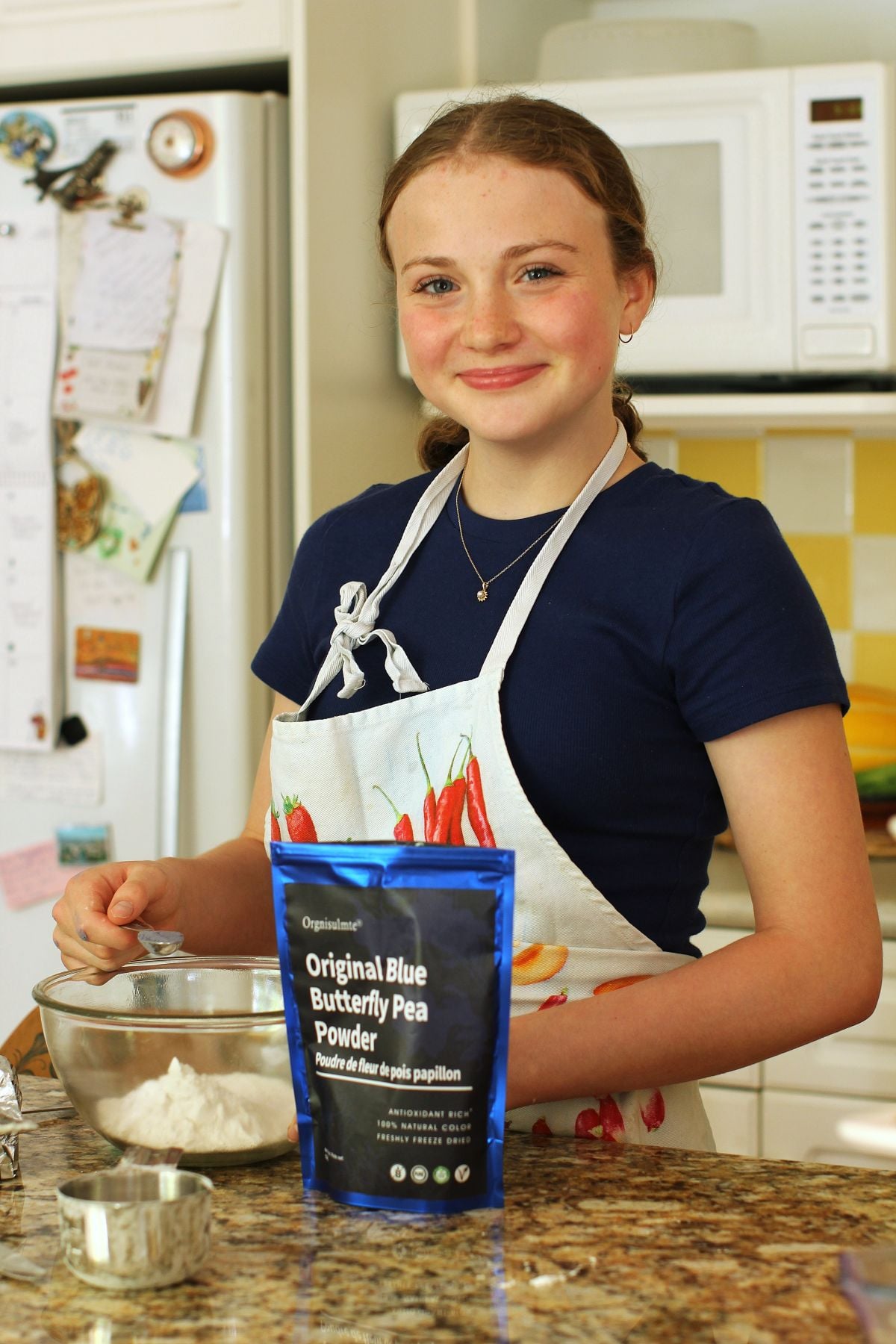 Amelia in the kitchen with apron on, stirring up a batch of dough.