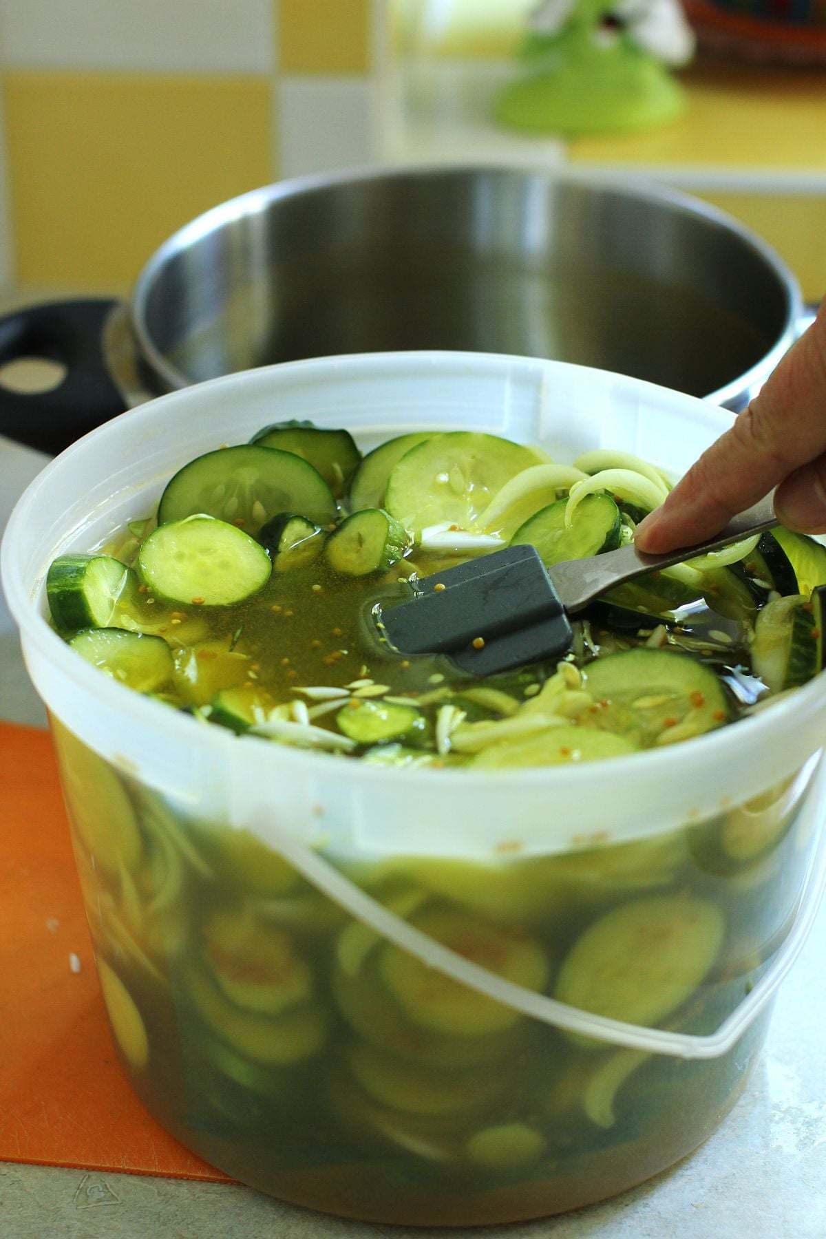 Pushing down on the cucumbers with a spatula to submerge them in the brine.