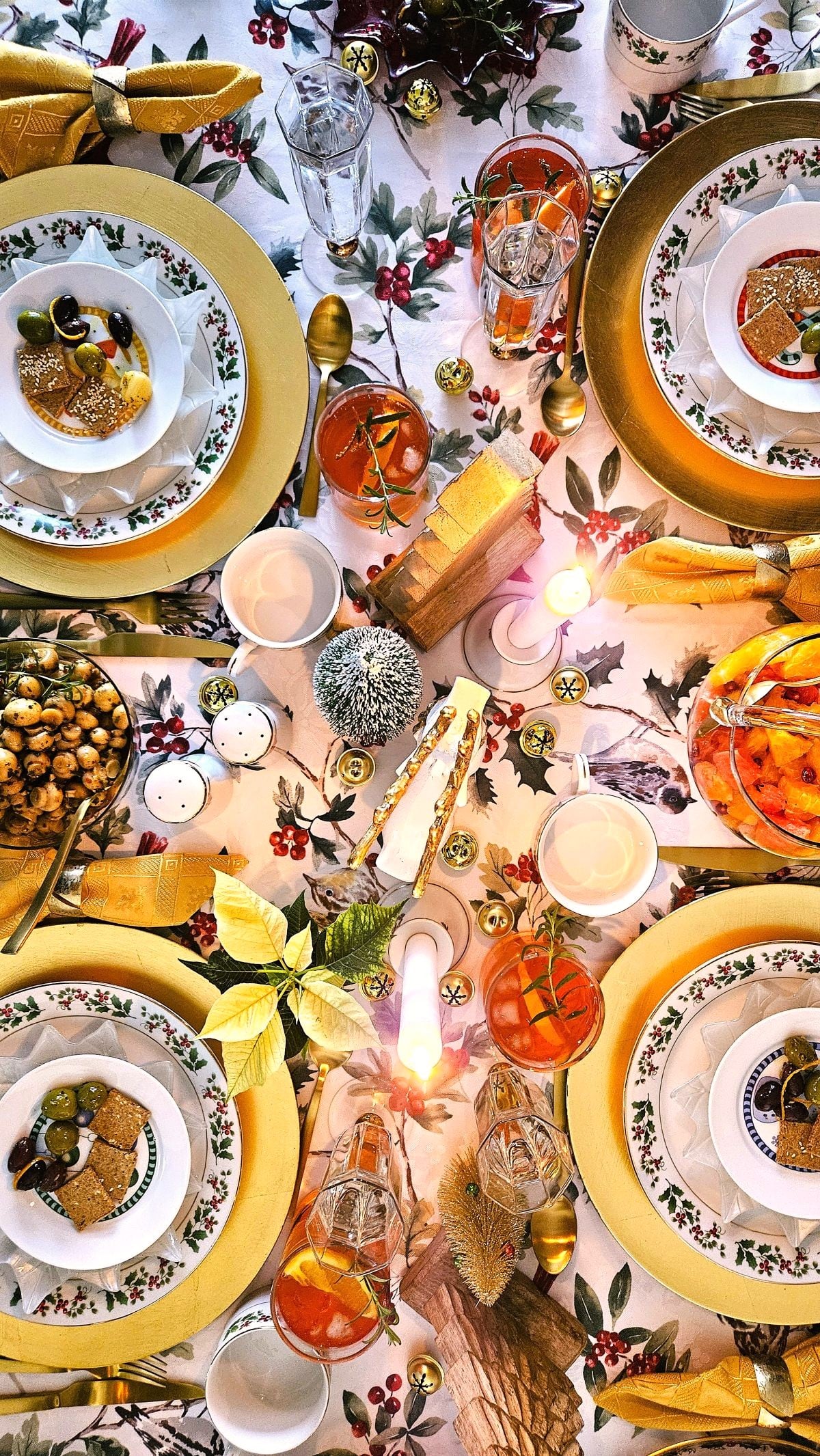 Top down view of Festive Luncheon Table with 4 table settings of Christmas dishes on gold chargers.