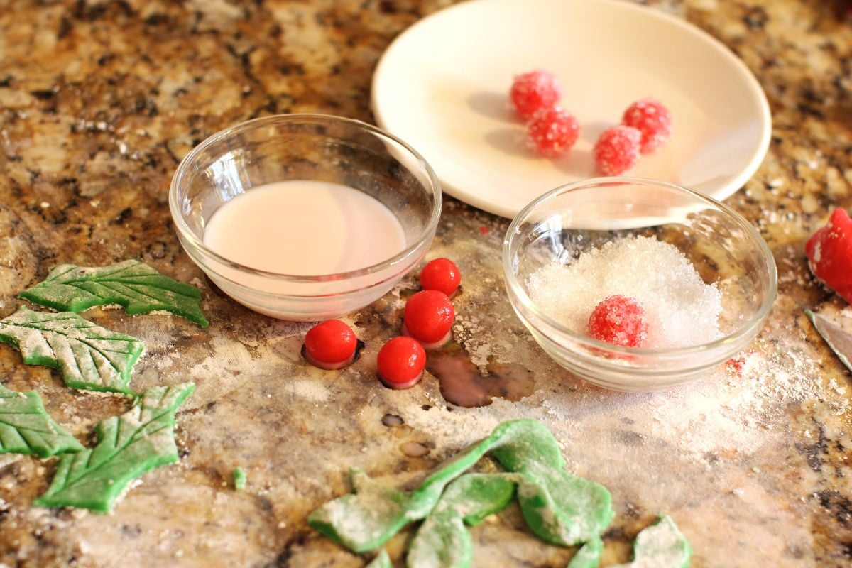 cut-out green marzipan leaves and small red holly balls, with small bowls of milk and sugar for dipping.