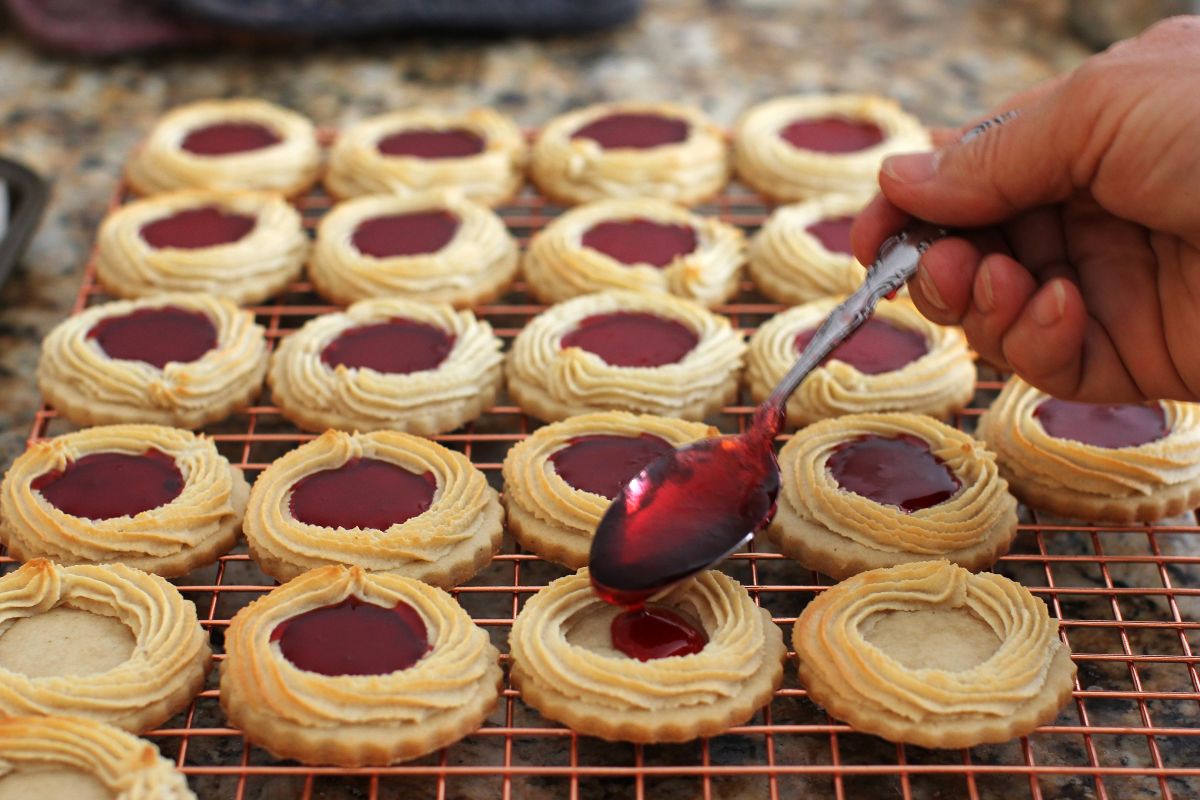 Filling the centers of the baked Marzipan Kränze with melted raspberry jelly.