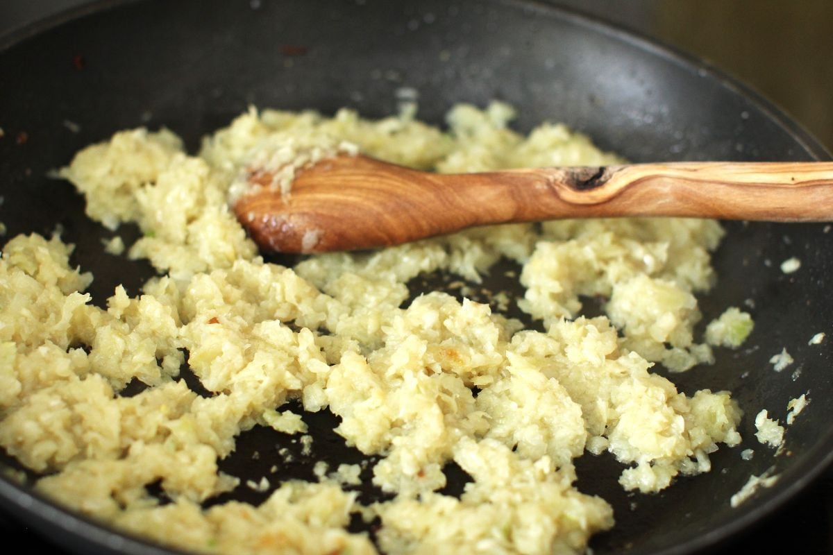 Frying finely chopped onions in a non-stick skillet for tomato sauce.