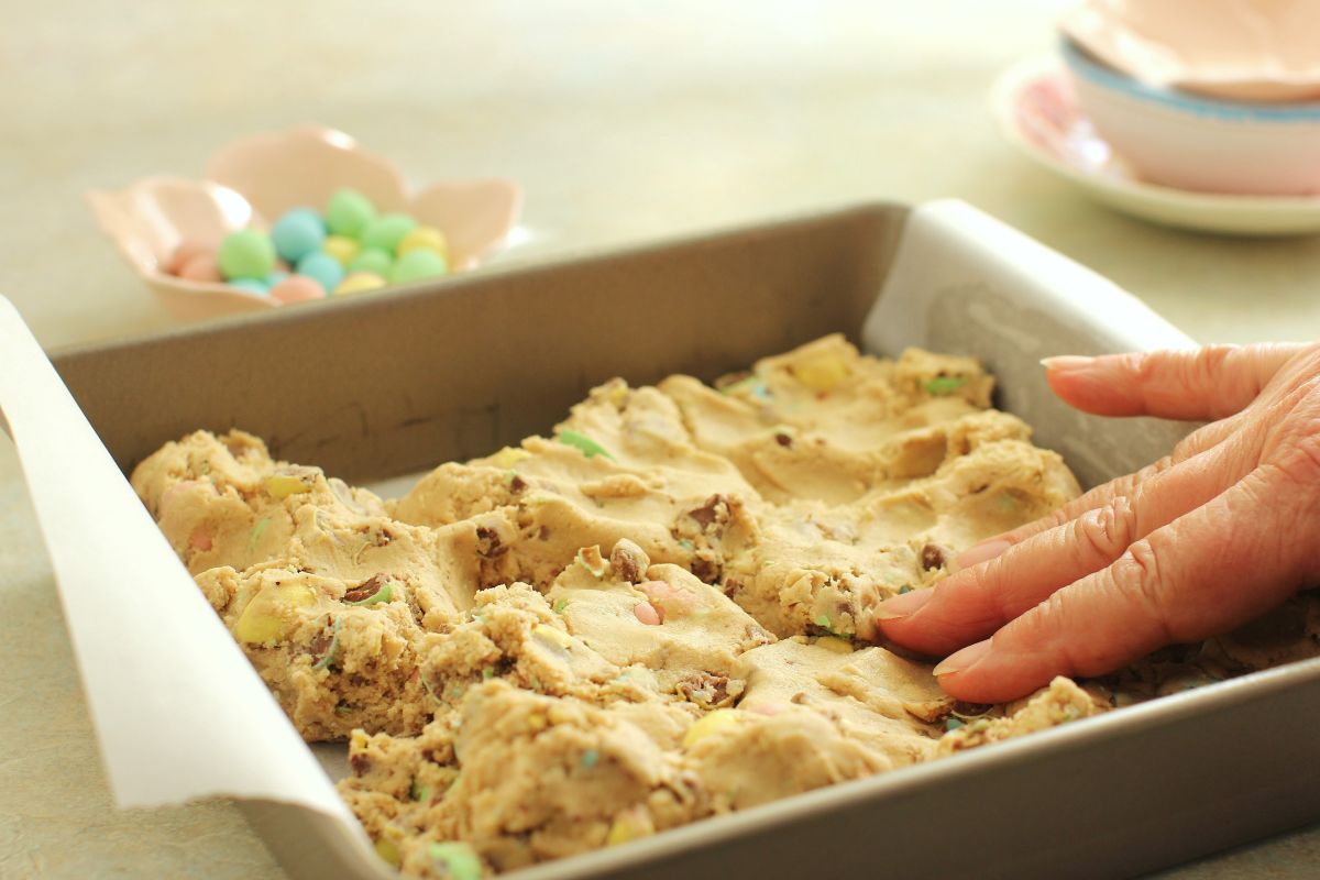 Pressing the cookie dough into a square pan.