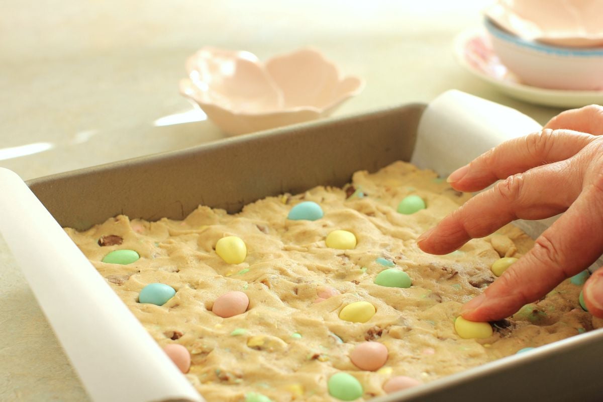 Pressing the whole mini eggs on top of the cookie dough in the baking pan.