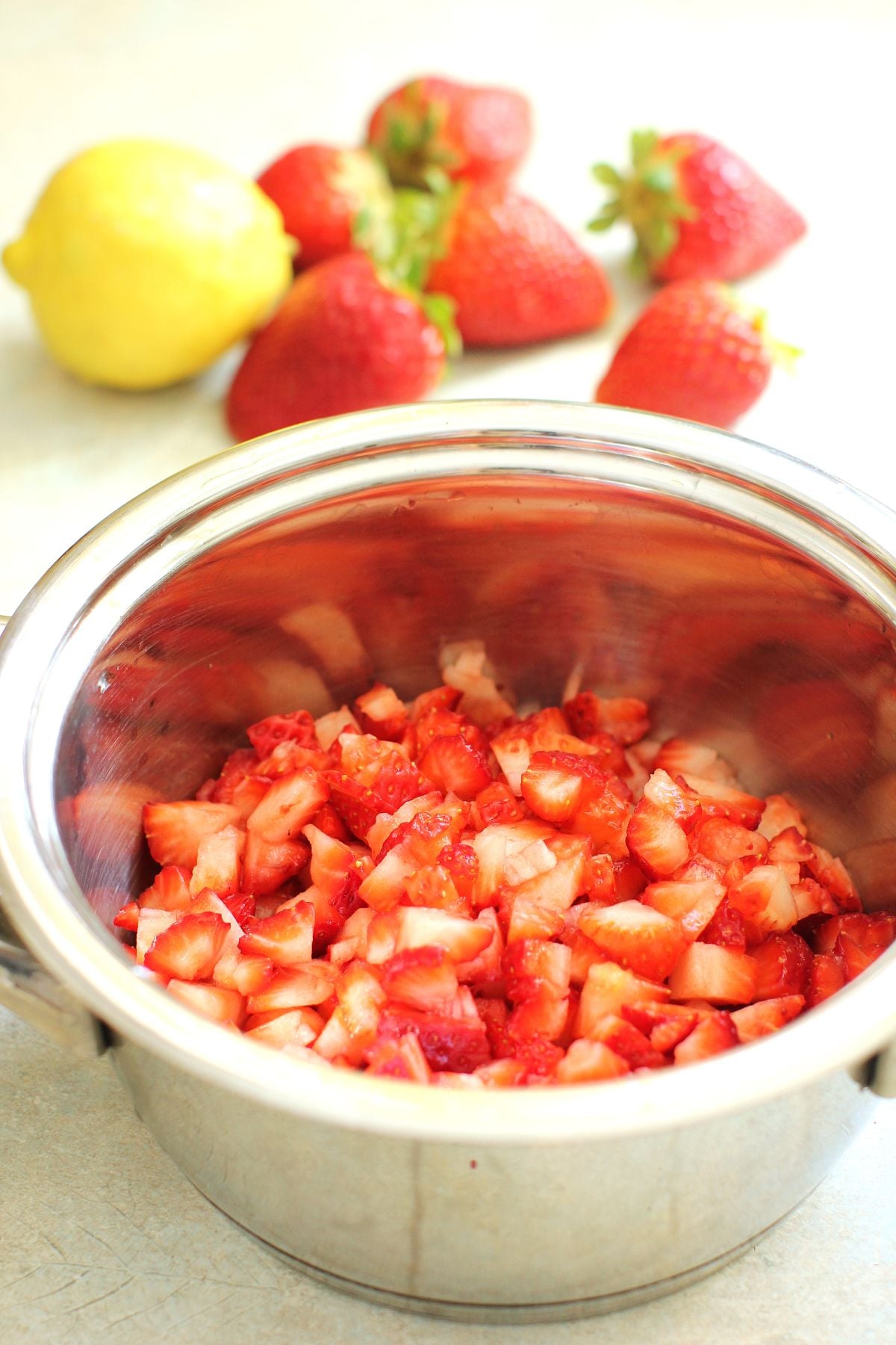 Small stainless steel saucepan with chopped strawberries in it.