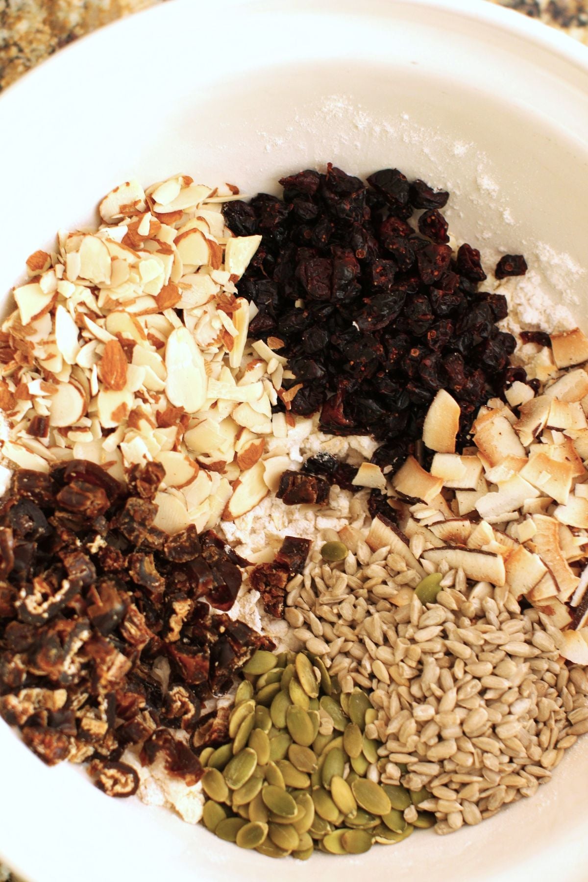 nut and seed ingredients added to the dry ingredients in the bowl in piles.