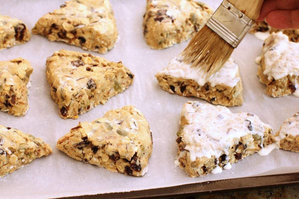 Brushing cream on the scones with a pastry brush.