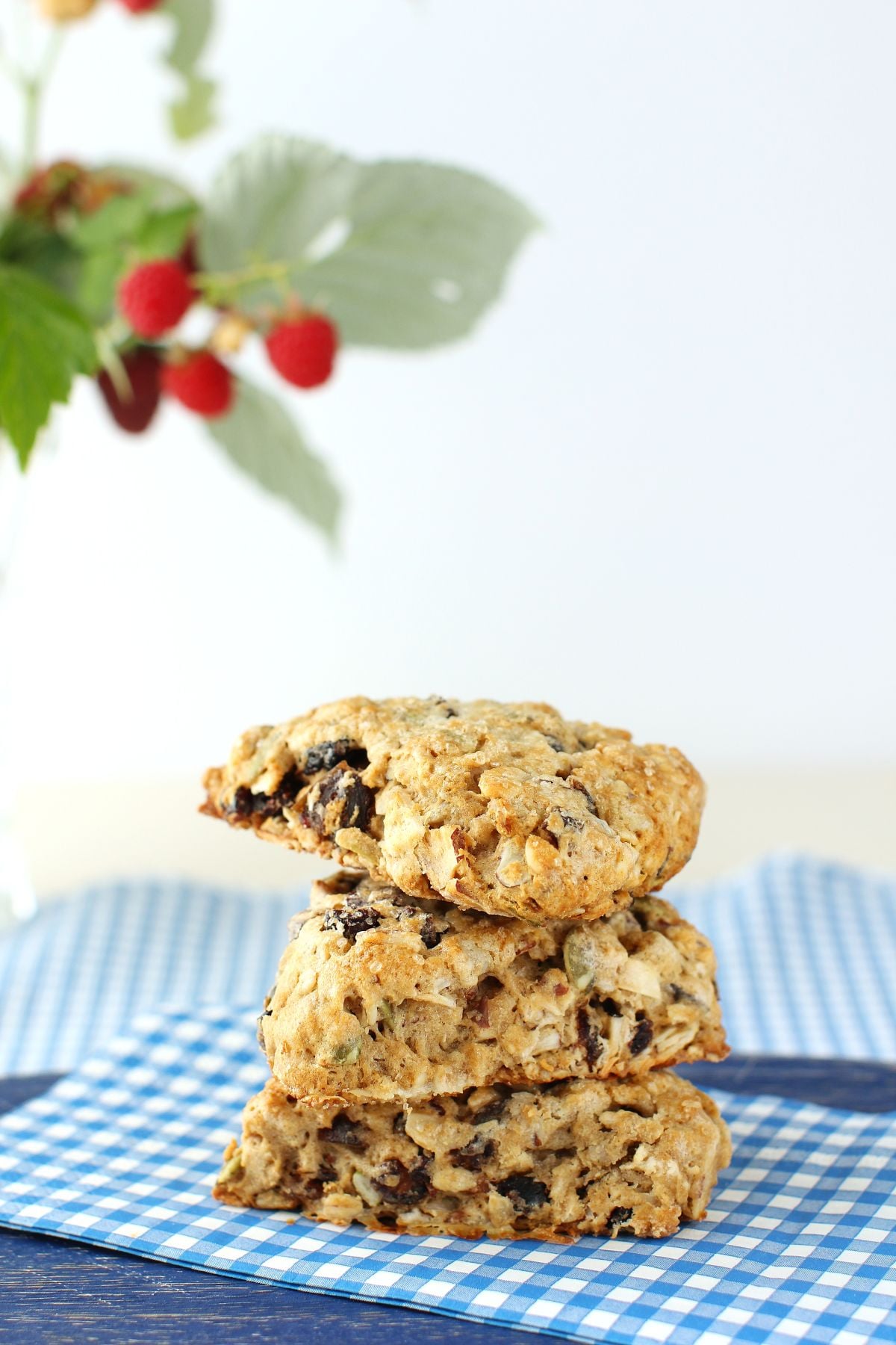3 Granola Scones stacked on top of each other on blue napkin, with raspberry bouquet above.