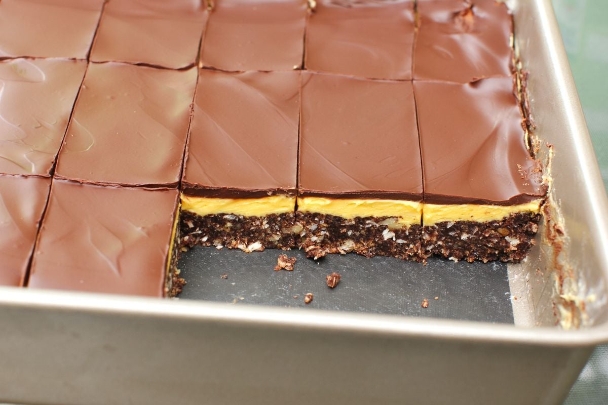 Pan of cut Nanaimo Bars with 3 pieces removed so you can see the layers in the remaining bars.