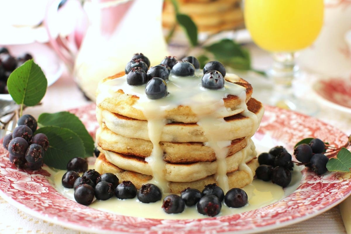 Close-up photo of a stack of saskatoon pancakes on a pink and white plate.