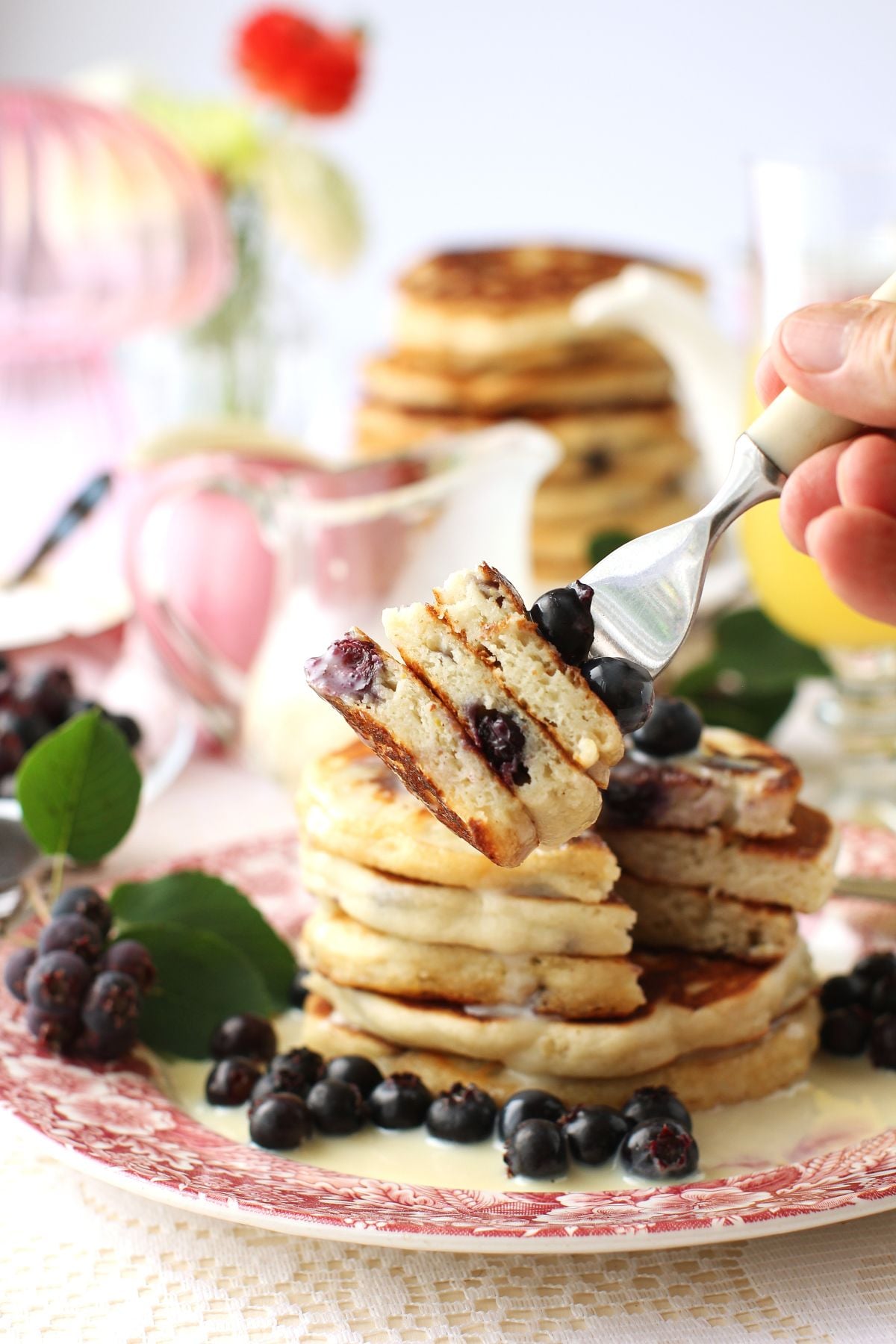 Fork holding 3 pieces of stacked saskatoon pancake in front of a stack of pancakes behind.