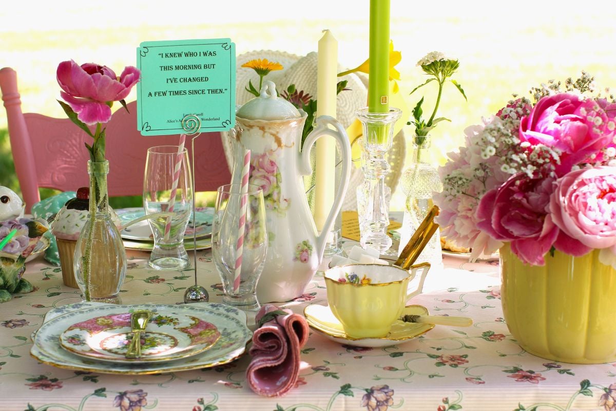 Mad Hatter's Tea Party tablescape with tall teapot, candles and dishes.