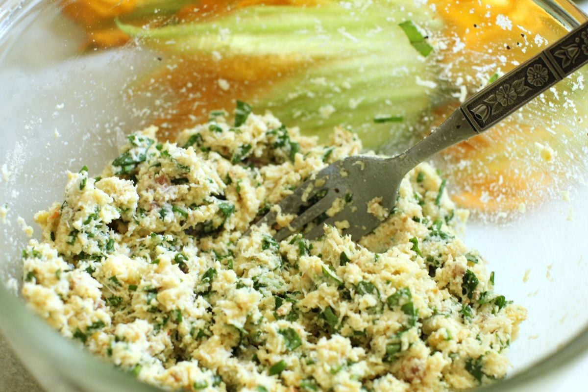 mixing up the crab filling ingredients in a bowl with a fork.