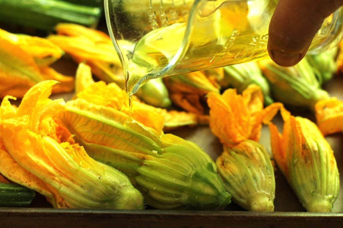 Drizzling the stuffed zucchini with olive oil.