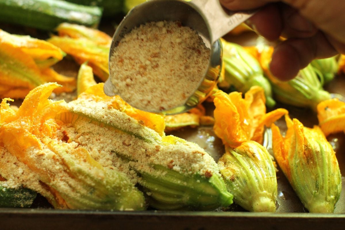 Sprinkling the stuffed zucchini blossoms with bread crumbs.
