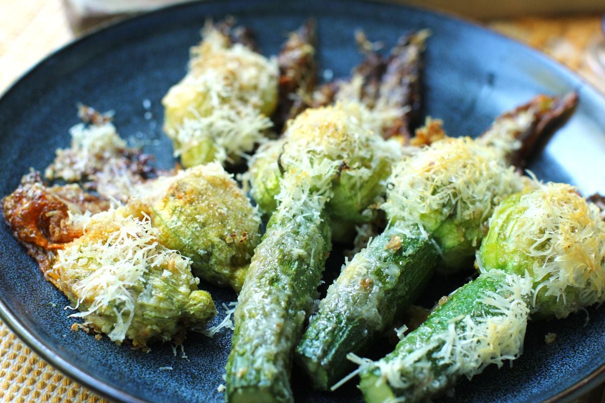 Close-up view of blue plate full of baked crab-stuffed zucchini blossoms.