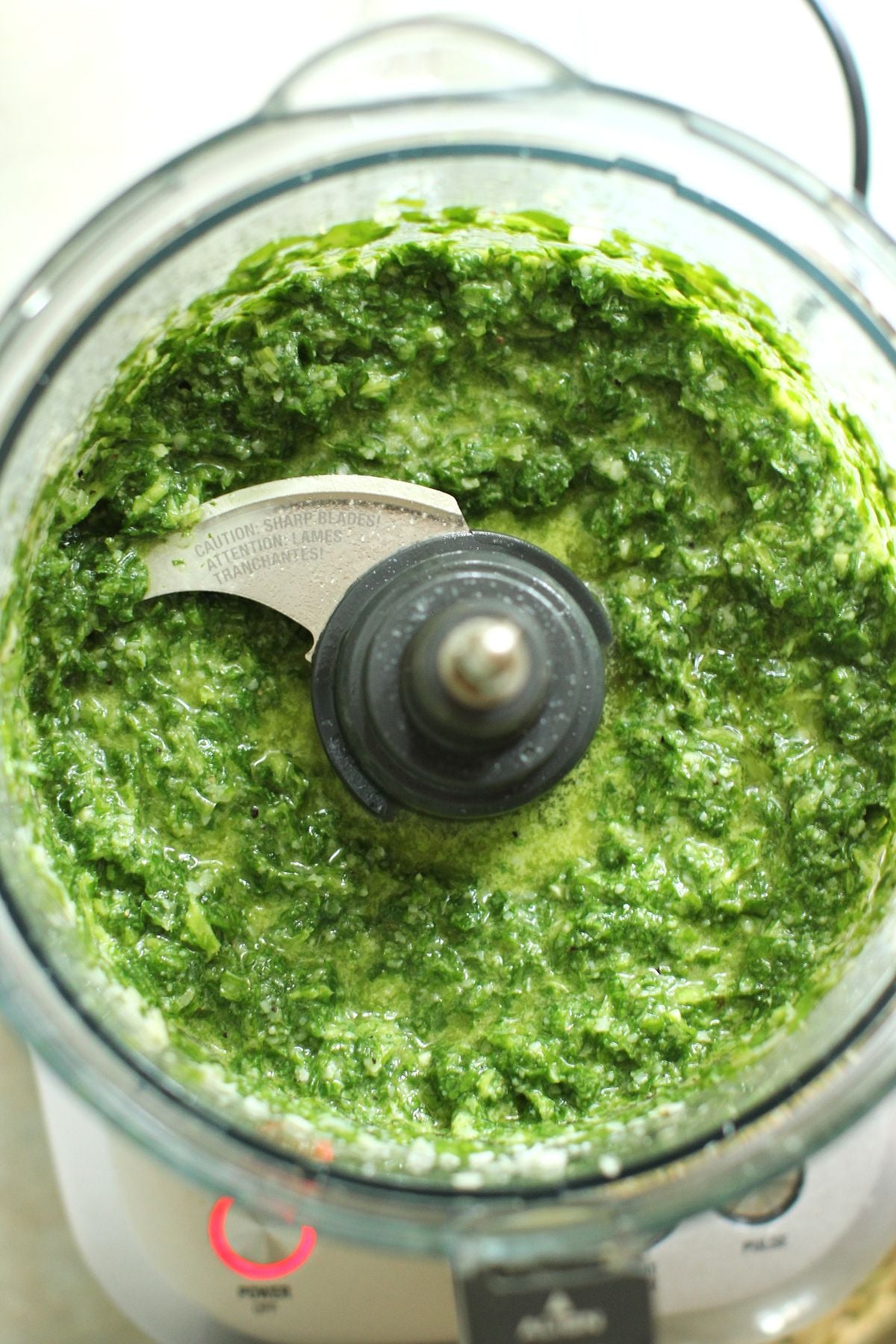 Looking down into the food processor canister to see the chunky green paste.