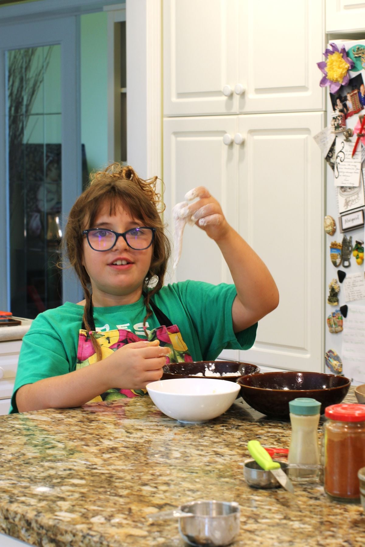 Willow holding up a floured chicken tender.