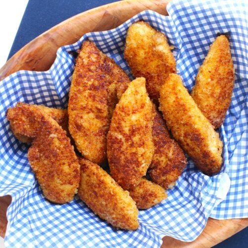 Square thumbnail photo of a pile of cheesy chicken fingers on blue & white checked paper in a wooden bowl.