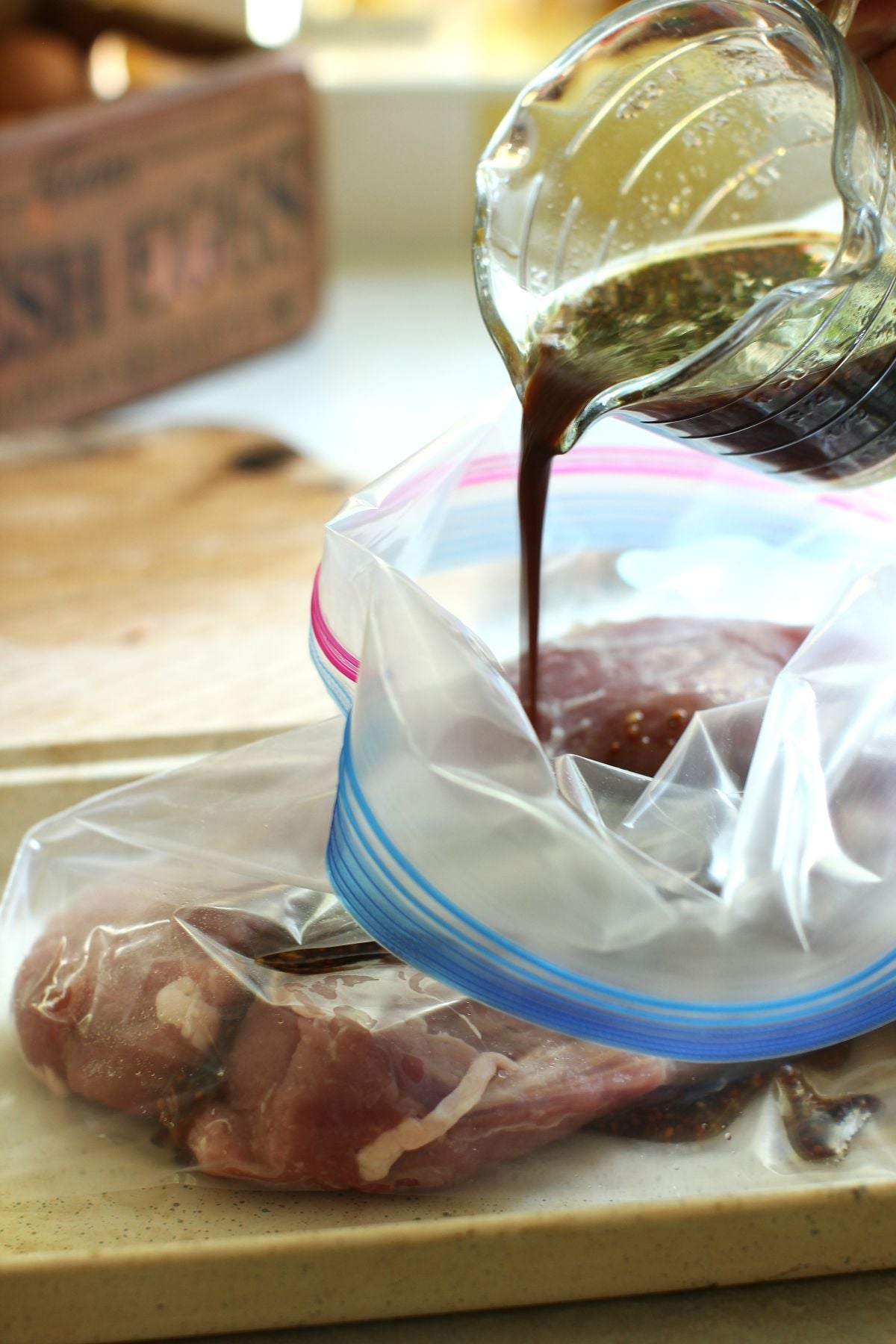 Pouring the marinade into the plastic bag containing two pork tenderloins.