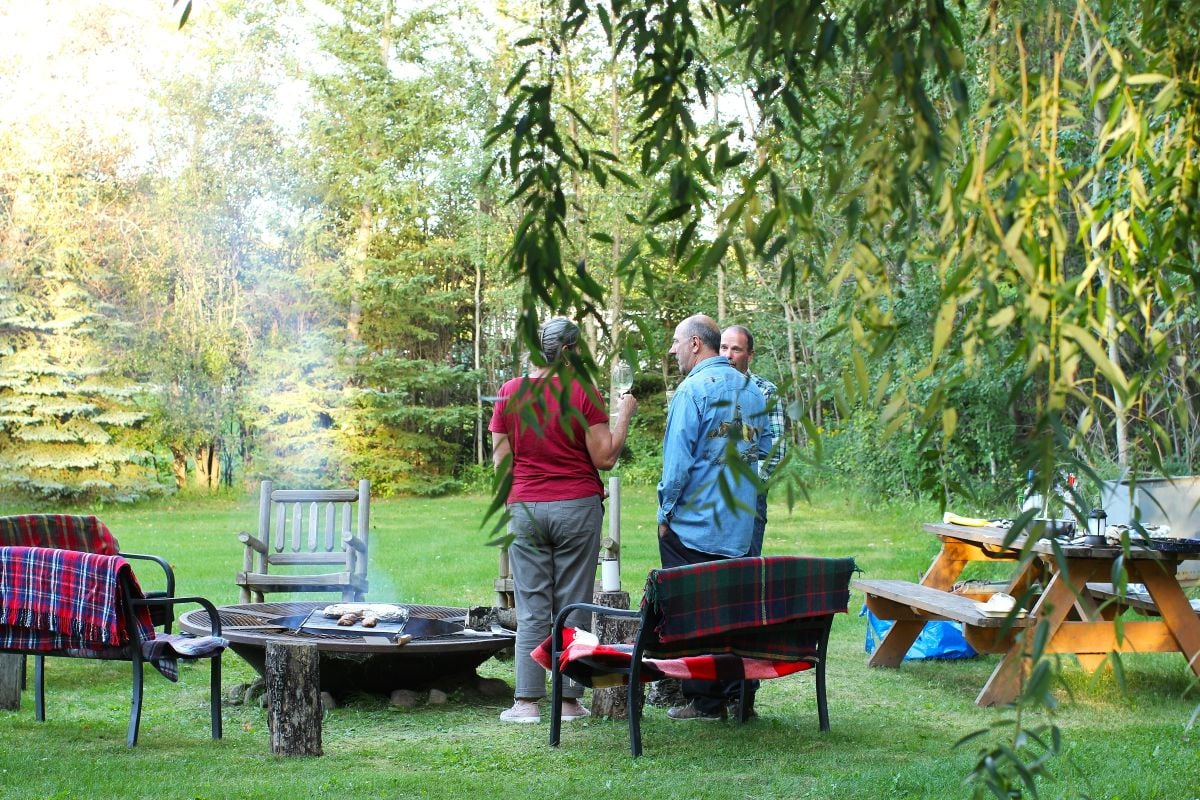 Standing around the campfire, enjoying a drink while we cook.