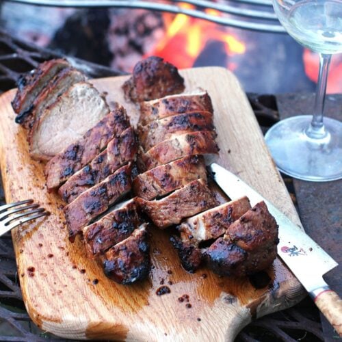 Square thumbnail photo of honey balsamic glazed tenderloin, sliced on a board, by the campfire.
